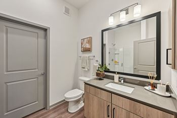 A bathroom with a toilet, sink, and mirror.